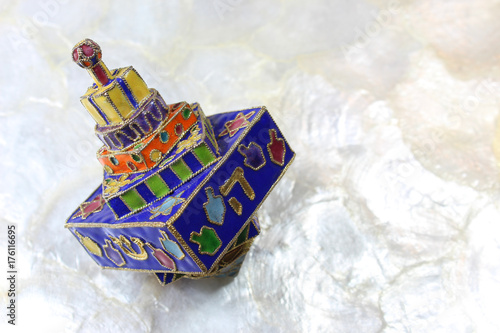 Festive colorful enameled Hanukkah dreidel on a soft white background
 photo