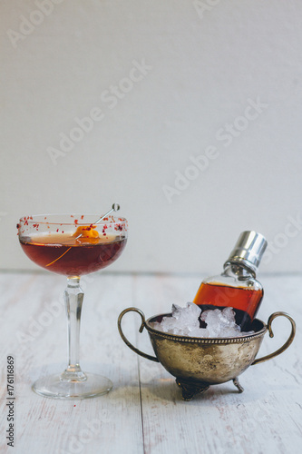 classic manhattan cocktail in a champagne saucer and in a flask on the rocks on white background photo