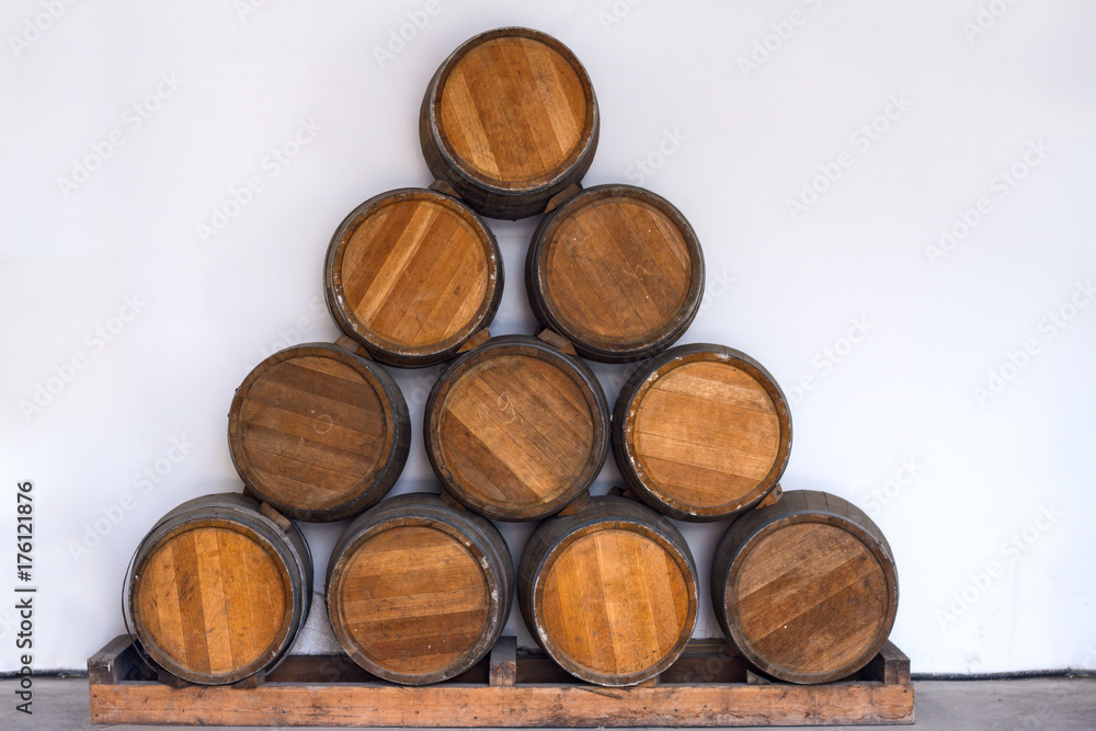 Oak barrels with wine in a winery laid out in the shape of a triangle on a white background.