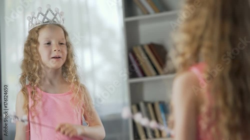 Little girl looking at mirror reflection, wearing fancy princess dress, magic
