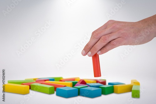 Composite image of cropped hand arranging blocks