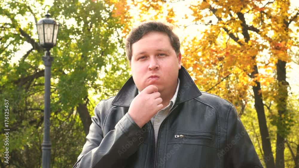 Thinking businessman looking at camera in autumn park Thinking businessman looking at camera in autumn park