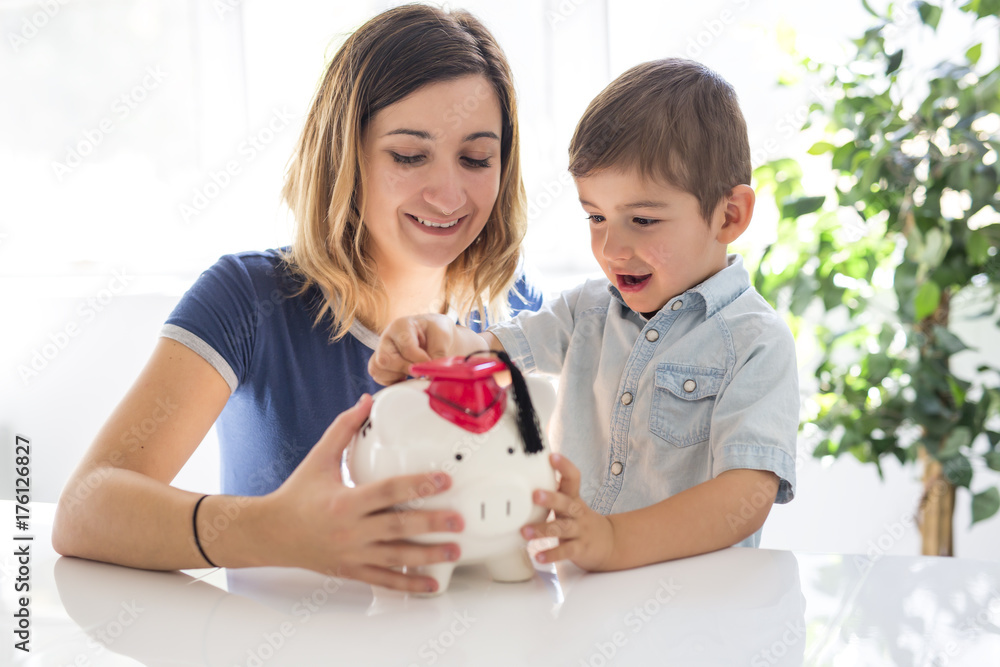 Little boy and his mother inserting money into piggy bank. Little boy and his mother inserting money into piggy bank.
