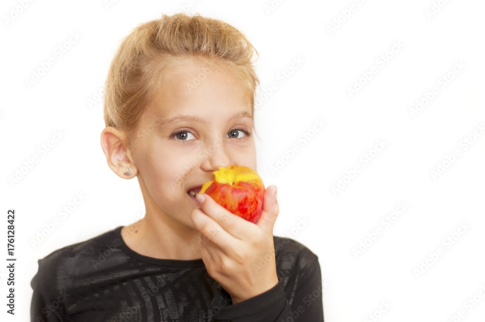 The girl eats peach and smiles. Portrait of a white background The girl eats peach and smiles. Portrait of a white background