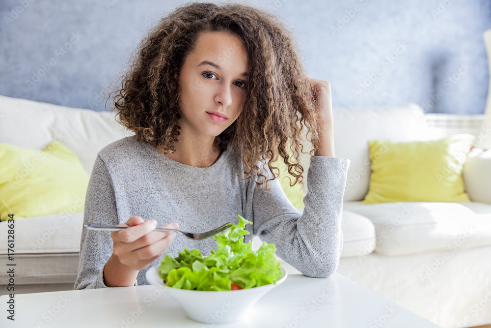 Curly hair teen girl eating salad