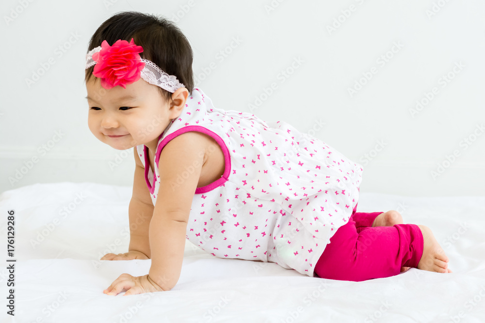 Portrait of adorable baby crawling on a white floor  with head band