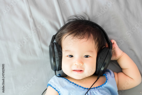Portrait of adorable baby lying on the bed with headphone, indoors