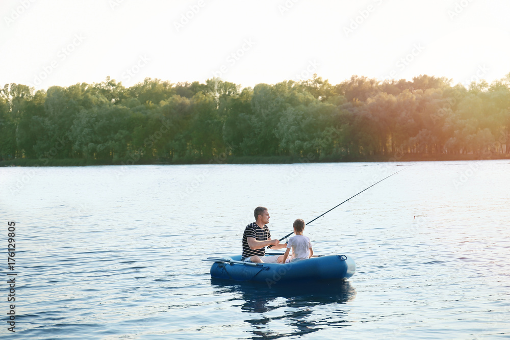 Father with son fishing from boat on river Father with son fishing from boat on river