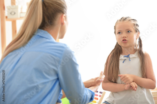 Young psychologist working with little girl in office