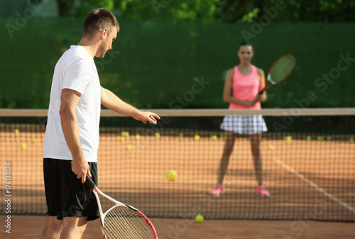 Young couple playing tennis on court © Africa Studio