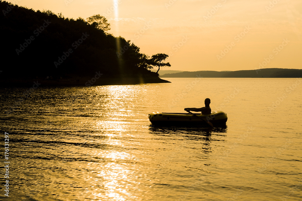 A beautiful golden sunset on the river. Lovers ride in a boat on a lake during a beautiful sunset. Happy couple woman and man together relaxing on the water. The beautiful nature around