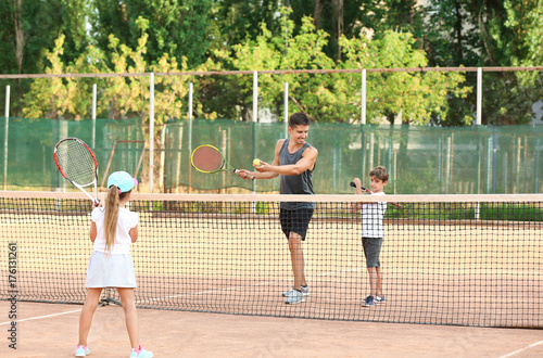 Young trainer with little children playing tennis on court © Africa Studio