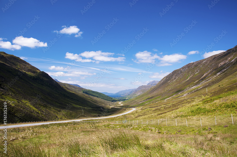 Scenic winding country road along a valley in the Scottish Highlands, United Kingdom; Concept for travel in Scotland