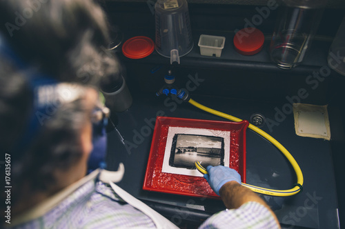 Man works on film black and white platinum print in laboratory.