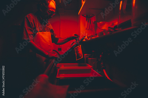 Man works on film black and white platinum print in laboratory.