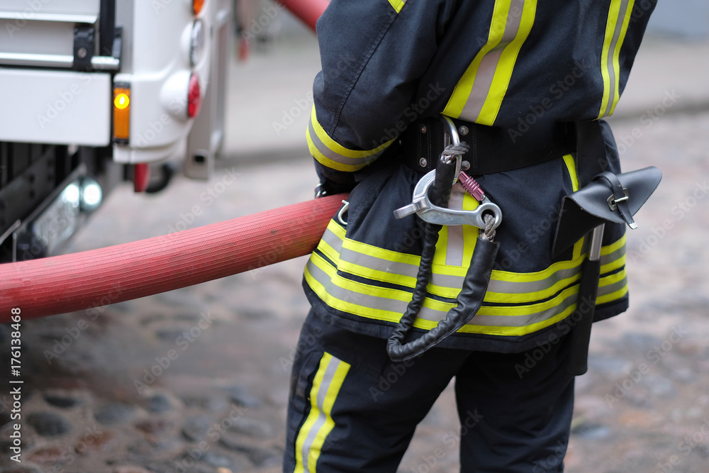 A member of the fire brigade holds a water supply hose from the fire engine A member of the fire brigade holds a water supply hose from the fire engine