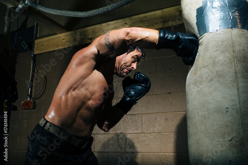 A boxer throws a hard punch at a punching bag in a gym photo