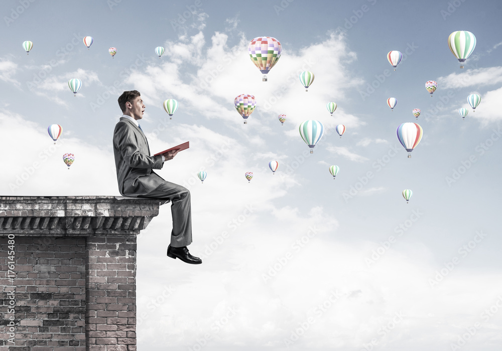 Man on roof reading book and aerostats flying in air Man on roof reading book and aerostats flying in air