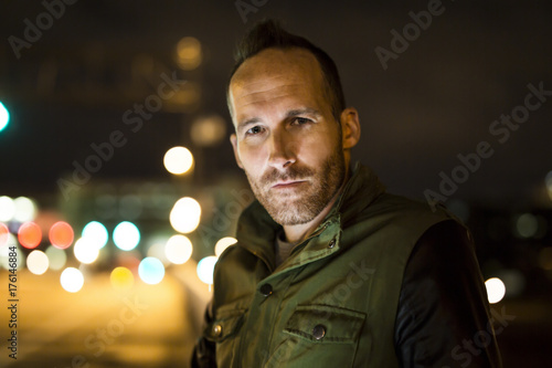 Attractive young man portrait at night with city lights behind him in Turin, Italy