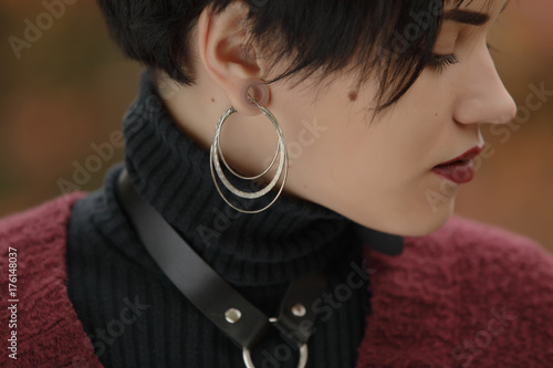 Fototapeta Closeup of unconventional woman portrait with tunnels on the ears and big earrin