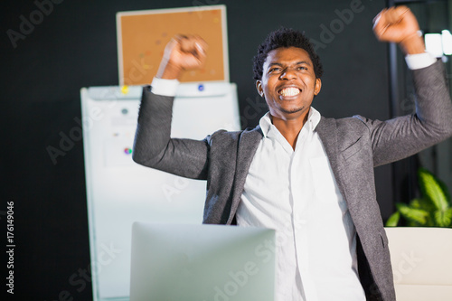 Wallpaper Mural Businessman at office, success gesture, goal reached, happy man. Hardworking male worker. Hipster afro american man at light office with computer monitor. Satisfied with job done Torontodigital.ca