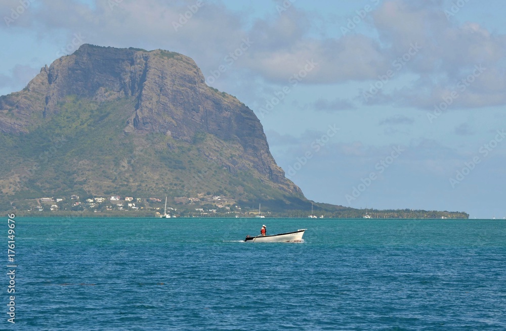 Obraz premium Pêcheur en barque, devant le Morne Brabant, montagne de l'île Maurice, Océan indien