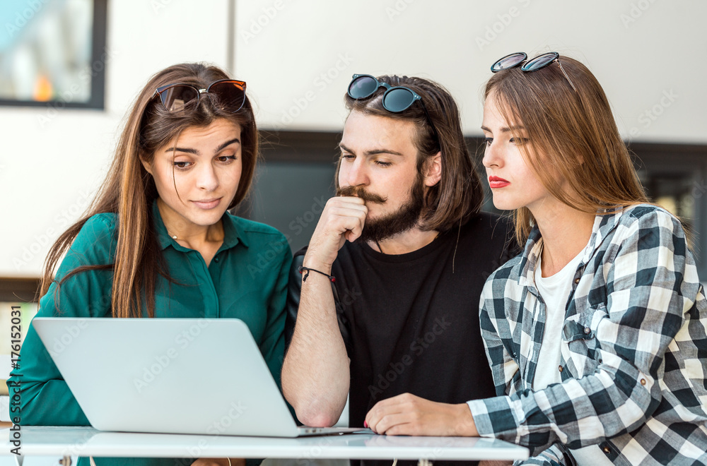 Group of students wear glasses have work conversation outdoor cafe, table with tablet computer before modern building wall, sunny day Group of students wear glasses have work conversation outdoor cafe, table with tablet computer before modern building wall, sunny day