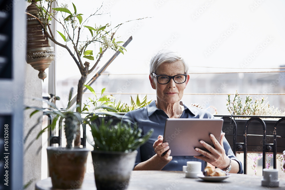Senior Woman Using Digital Tablet On Balcony