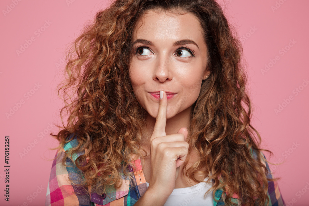 Portrait of pensive smiling woman showing silence gesture isolated Portrait of pensive smiling woman showing silence gesture isolated