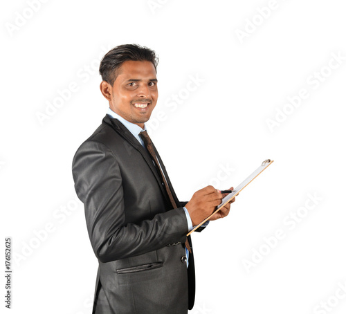 Businessman in black suit happily writing on clipboard over white background