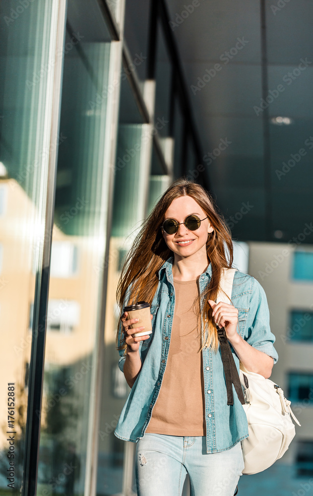 Fototapeta premium Hipster stylish girl wear sunglasses walk and hold cup of coffee