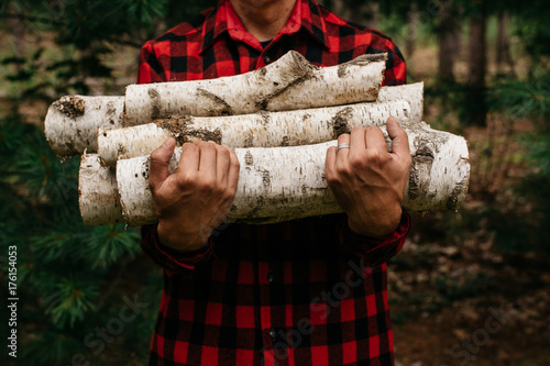 Men in red and black flannel holding firewood