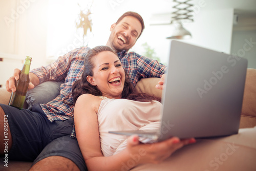 Young couple sitting in the living room and using laptop © ivanko80