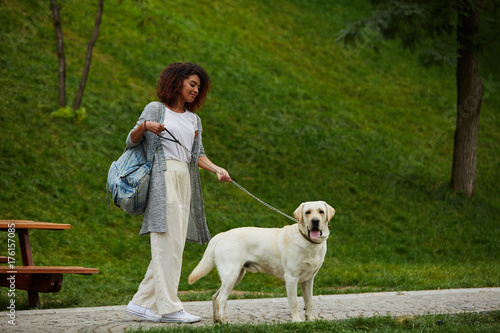 Pretty young lady walking with dog in park in the morning