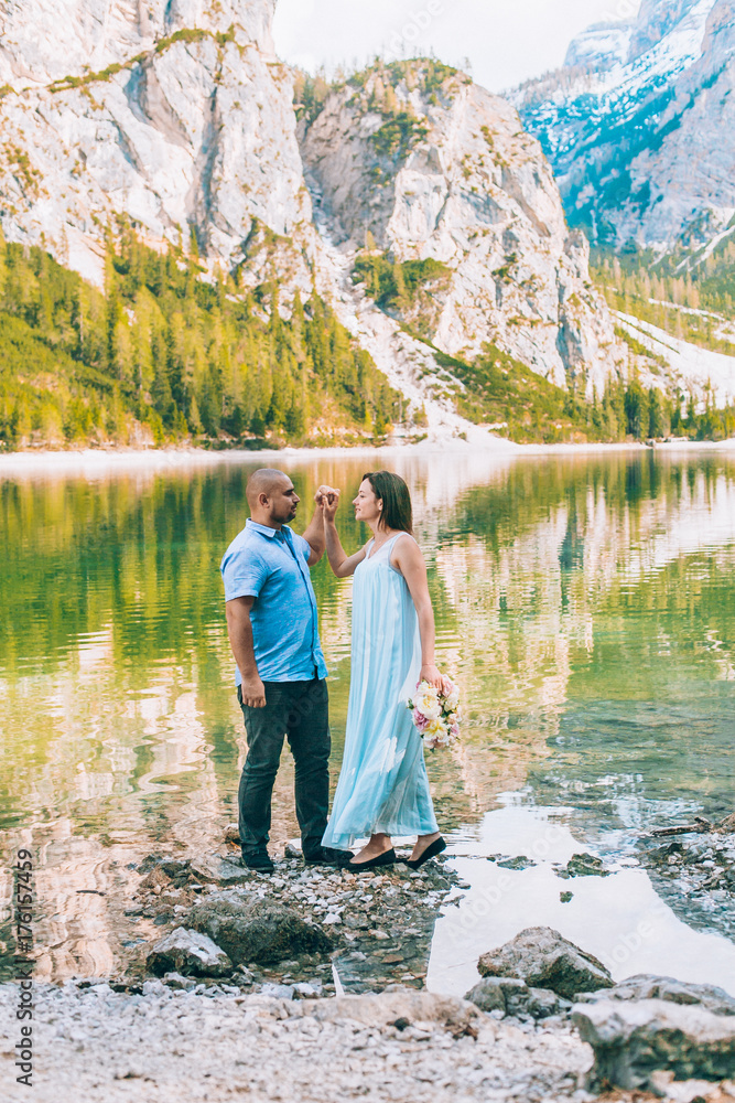 Young couple near lake lago di braies,Dolomite,Italy hold the hand stand at the stone at lake.