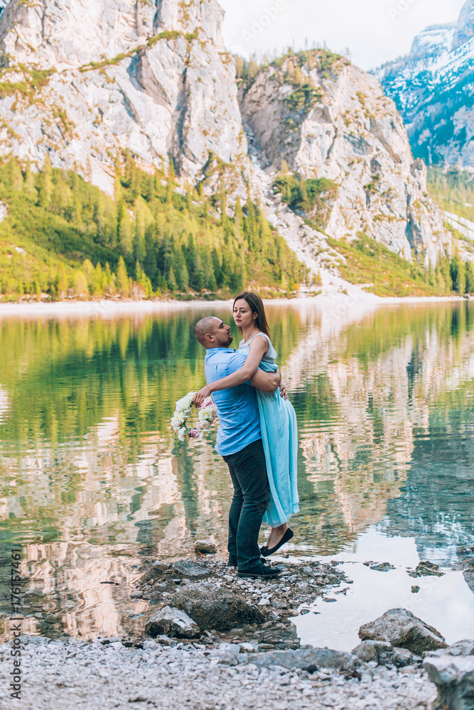 Young couple near lake lago di braies,Dolomite,Italy hold the hand stand at the stone at lake.