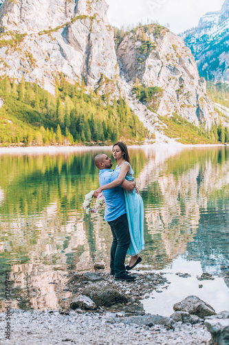 Young couple near lake lago di braies,Dolomite,Italy hold the hand stand at the stone at lake.