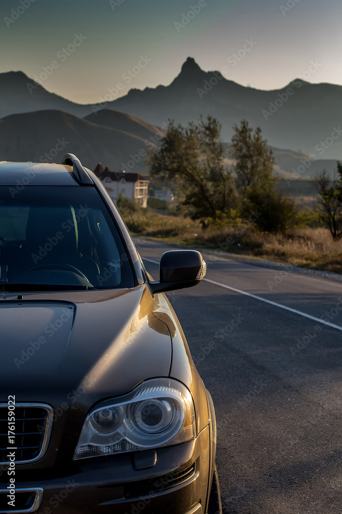 A modern car on the road in the mountains, on vacation. At sunset, in summer