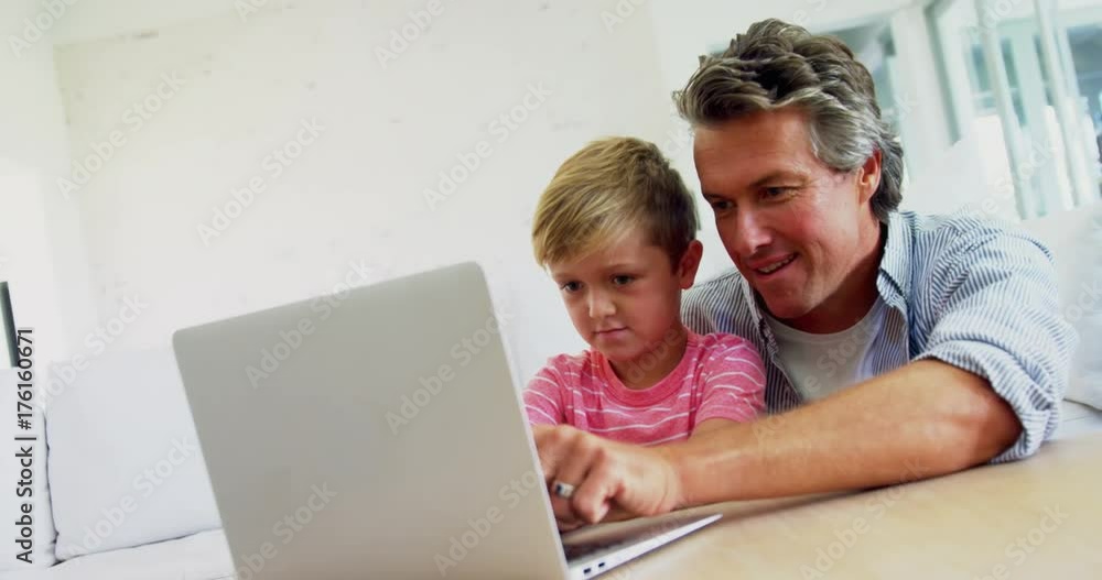 Father and son using laptop in living room Father and son using laptop in living room