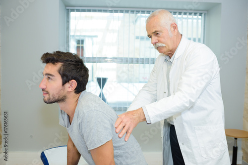 doctor examining her patient shoulder in medical office