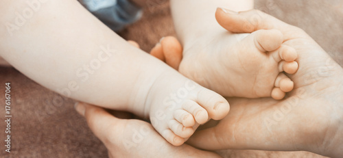 The panorama of baby feet in mother hands. Newborn baby feet, concept of happy family. Fake color tone of photo..