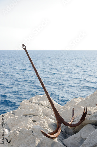 Old anchor on the rocky shore of the ocean. 
