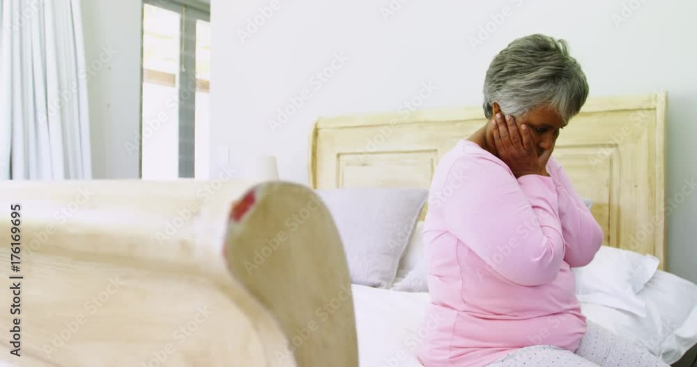 Tense senior woman sitting on bed in bedroom Tense senior woman sitting on bed in bedroom