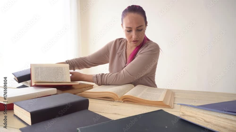 the girl with the pink hair is sitting at the table reading a book the girl with the pink hair is sitting at the table reading a book