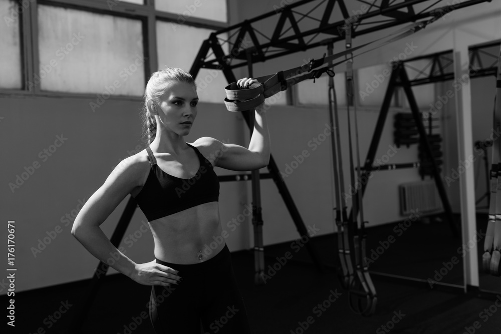 Fototapeta premium Sporty woman doing TRX exercises in the gym