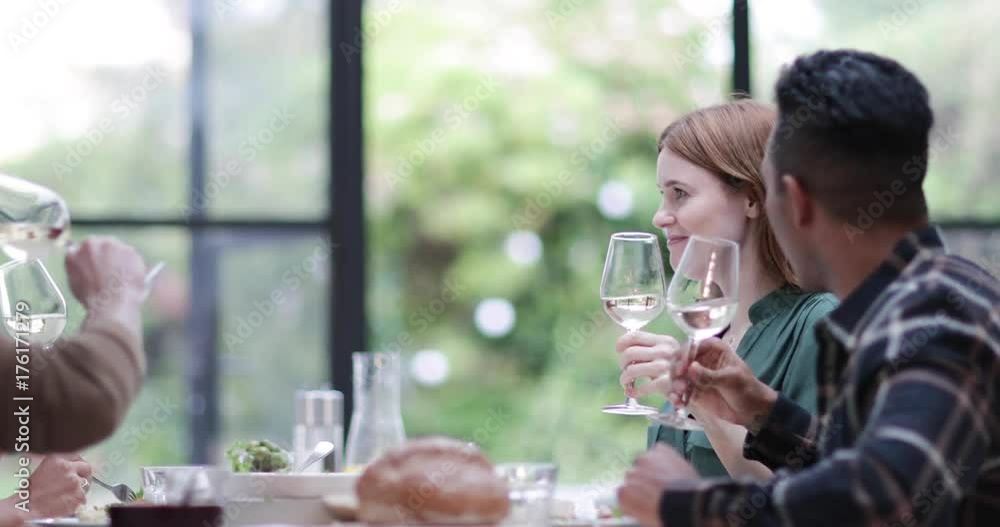 Friends clinking glasses over a meal together Friends clinking glasses over a meal together