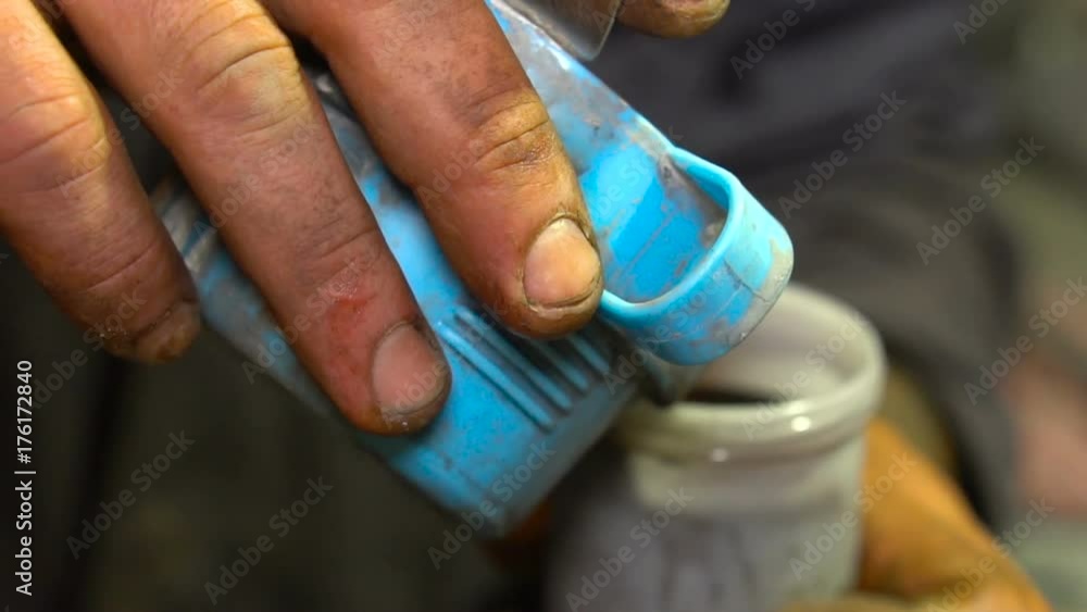 Man pours paint in a plastic container Man pours paint in a plastic container