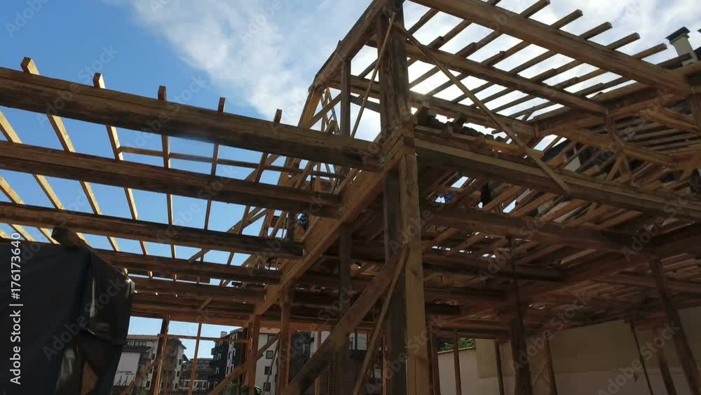 Wooden house construction site with sun shining on blue sky Wooden house construction site with sun shining on blue sky
