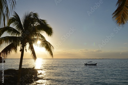 Barque de pêcheur avec coucher de soleil et palmier sur l'île Maurice, Océan indien © Didier San Martin