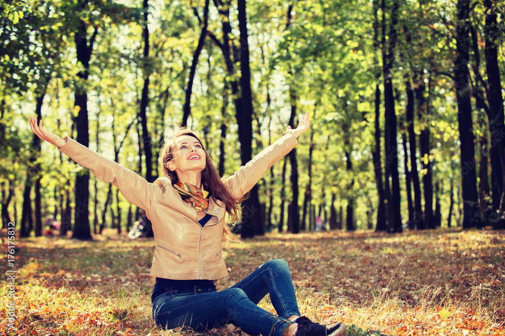 girl in autumn scenery sits on the ground with raised hands girl in autumn scenery sits on the ground with raised hands